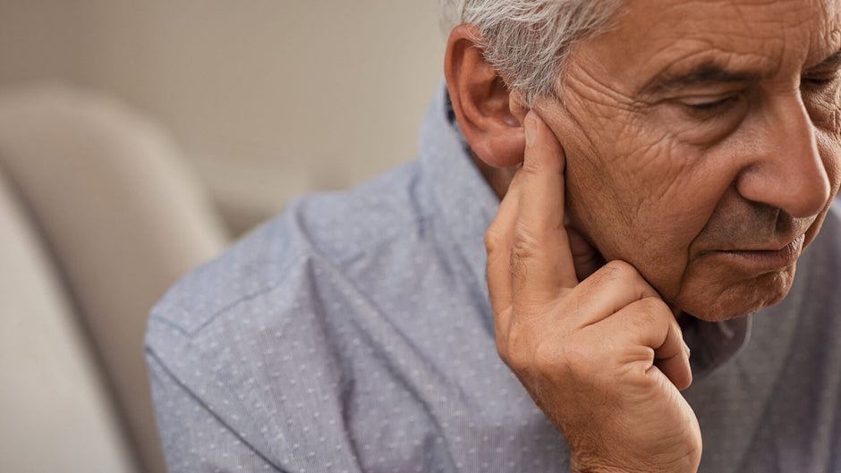Man holding ear with a view to buying hearing aids